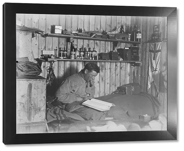 George Murray Levick seated on his bunk, reading