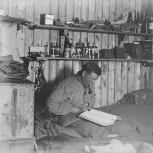 George Murray Levick seated on his bunk, reading