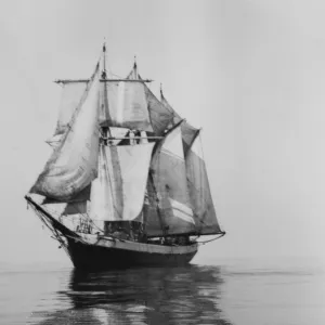 Penola at sea with sails set, reflections in foreground