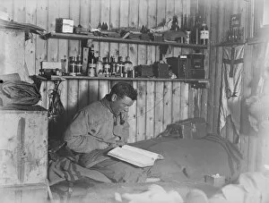 George Murray Levick seated on his bunk, reading